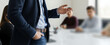 © Renderis - Business meeting with a speaker gesturing in front of a group of people.