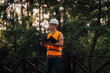 © Ljustina - Forest engineer inspecting a wooden bridge in a park, holding a clipboard