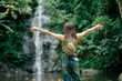 © pichet - A traveler stands with arms wide open, celebrating the moment in front of a stunning waterfall. A joyful and inspiring image of adventure and living life to the fullest.