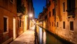 Night scene of a narrow canal in Venice, Italy, with illuminated buildings and a calm waterway