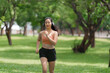 © Phimwilai - Young asian sportswoman running in the park listening music with headphones