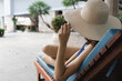 © 9nong - Relaxed anonymous woman wearing blue summer swimwear with sun hat, lying on pool bench in resort and spa, concept of summer vacation travel, relaxation, sunbathing, sunlight exposure