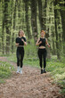 © dsheremeta - Young women running together on forest trail path
