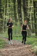 © dsheremeta - Two women jogging through lush forest trail