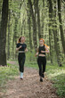 © dsheremeta - Two women running in forest wearing sportswear enjoying exercise outdoors