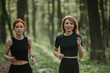 © dsheremeta - Two women jogging in a lush forest trail