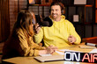 © Pixel-Shot - Couple of radio presenters recording at table in studio