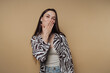 © bodnarphoto - portrait of young cheerful woman in a zebra print shirt blowing a kiss, showcasing joy and liveliness on calm yellow background