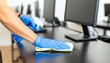 © luzaein - Worker in protective gloves cleaning an office computer desk with disinfectant spray