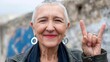 © t.sableaux - Confident senior woman with short hair is smiling and making a rock sign gesture outdoors, showcasing her vibrant personality and joyful spirit