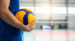 © Kaluya Stock - Male volleyball player holding a ball on an indoor court, ready to serve or play