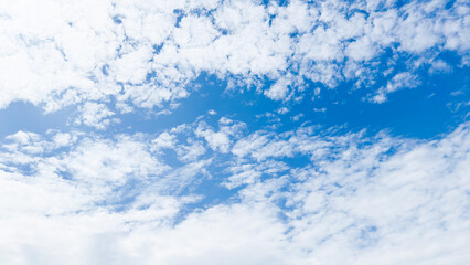 Wall Mural - A stunning background of a clear blue sky with delicate white cloud formations on a bright sunny day. Peaceful and serene atmosphere, suitable for themes related to nature, weather, relaxation, travel
