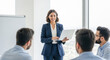 © Soem - A businesswoman standing in front of a group of colleagues, holding a laptop and smiling.