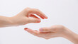© Graphic Store - Close up of two human hands interacting with one hand offering something to the other on a white background