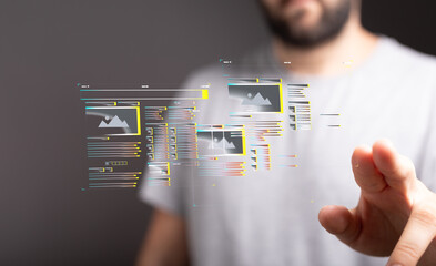 a man interacts with a transparent digital screen showing website design elements. modern technology