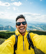 © Davide Angelini - Young hiker man taking selfie portrait on the top of mountain - Happy guy smiling at camera - Hiking, sport, travel and technology concept - Bright filter - Vertical photo