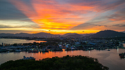 Wall Mural - A breathtaking view of a vivid yellow, pink and purple sunset reflecting on calm sea. This serene scene captures the beauty of nature's colors at Phuket fishing port. colorful cloud scape background