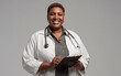 © Korkiat - Portrait of a smiling Black woman doctor wearing a stethoscope and holding a medical notebook against a gray background,