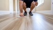 © Artsaba Family - A man crouches to inspect a sample of wooden flooring in a well lit hallway, emphasizing precision and craftsmanship