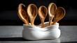© afrah - Olive wood spoons in a white ceramic organizer on dark espresso stone with gentle side lighting and smooth highlights