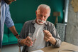 © Miljan Živković - Nurse assisting elderly man taking medication at home