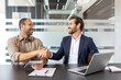 © Liubomir - Two businessmen shake hands during a meeting, symbolizing agreement and partnership in a modern office environment.