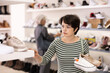 © JackF - Adult woman buyer chooses pair of sneakers in shoe store