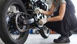 © Abdul Rosid - A professional mechanic is inspecting or repairing the rear end of a motorcycle, focusing on the chain and wheels. This image shows the vehicle maintenance process in detail, h,mechanic changing wheel