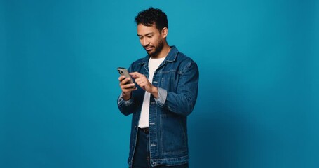 Scroll, phone and smile with man in studio for social media, text message and communication. Connection, browsing online and chat with person and mobile on blue background space for network and app