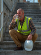 © Wee Ha - Construction Worker Suffering From Heatwave While Resting And Drinking Water Outside Building Site