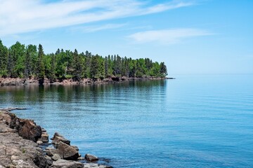 Wall Mural - serene rocky shoreline with calm blue lake.