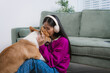 © NanSan - Asian woman sits on the floor at home, smiling while playing, training, and feeding her adorable corgi. Their loving bond reflects joyful pet care, indoor companionship, and happy lifestyle moments
