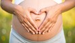 © Sherna - Woman holding her pregnant belly with hands in heart shape
