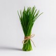 © Serva - Bunch of vibrant green chives tied with twine, casting a gentle shadow on a white surface