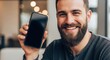 © Creative Hero - Smiling bearded man holding a smartphone with a black screen in his hand, close-up shot mobile