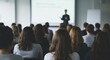 © DSGNCO - Captivated Audience in a Lecture Hall, View from Behind with Blurred Speaker.