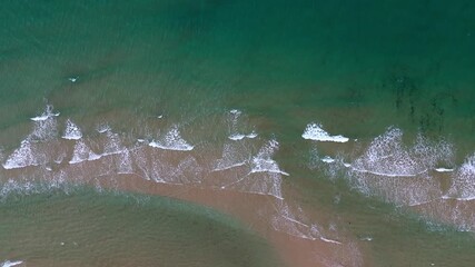 Wall Mural - Aerial view of ocean waves caressing sandy beach in tranquil coastal scene