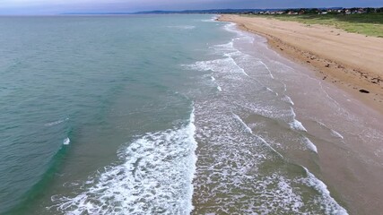Wall Mural - Aerial view of serene coastline with gentle waves lapping the sandy beach
