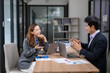 © Wasana - Two people are sitting at a table in a room, one of them is smiling