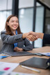 © Wasana - A woman shakes hands with another woman in a business setting
