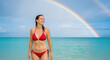 © Everlasting Dreams - Double rainbow after a rain storm over the pacific ocean, happy woman in a red bikini enjoys cooling of in water and candidly poses for a perfect memorable holiday moment to remember.