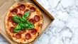 © Putra - Pizza in a cardboard box on a marble surface.