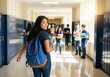 © ALF photo - Élève heureuse avec un sac à dos marchant dans un couloir d'école
