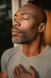 © misunderst00d - Middle-aged Black man standing on wooden porch, eyes closed, breathing deeply, off-grid home