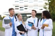© New Africa - Medical students in uniforms with backpacks and notebooks outdoors, selective focus
