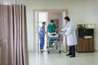 © Ekkasit A Siam - Medical team moving injured asian male patient on stretcher into hospital emergency room while senior caucasian male doctor standing beside door preparing to assist during urgent care process