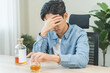 © KMPZZZ - Health care alcoholism drunk, fatigue asian young man hand holding glass of whiskey, depressed male drink booze on table at home. Treatment of alcohol addiction, suffer abuse problem alcoholism
