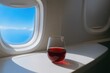 © Nadia - Glass of red wine on airplane tray table with sky view through window
