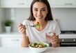 © Alper AI - Happy woman enjoys a fresh, healthy salad and drinks water in her kitchen.