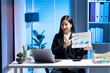 © Kritdanai - Analyzing the Data: A businesswoman presents data in a modern office setting, the soft blue light of a modern office illuminating her focus, showing the essence of information.
